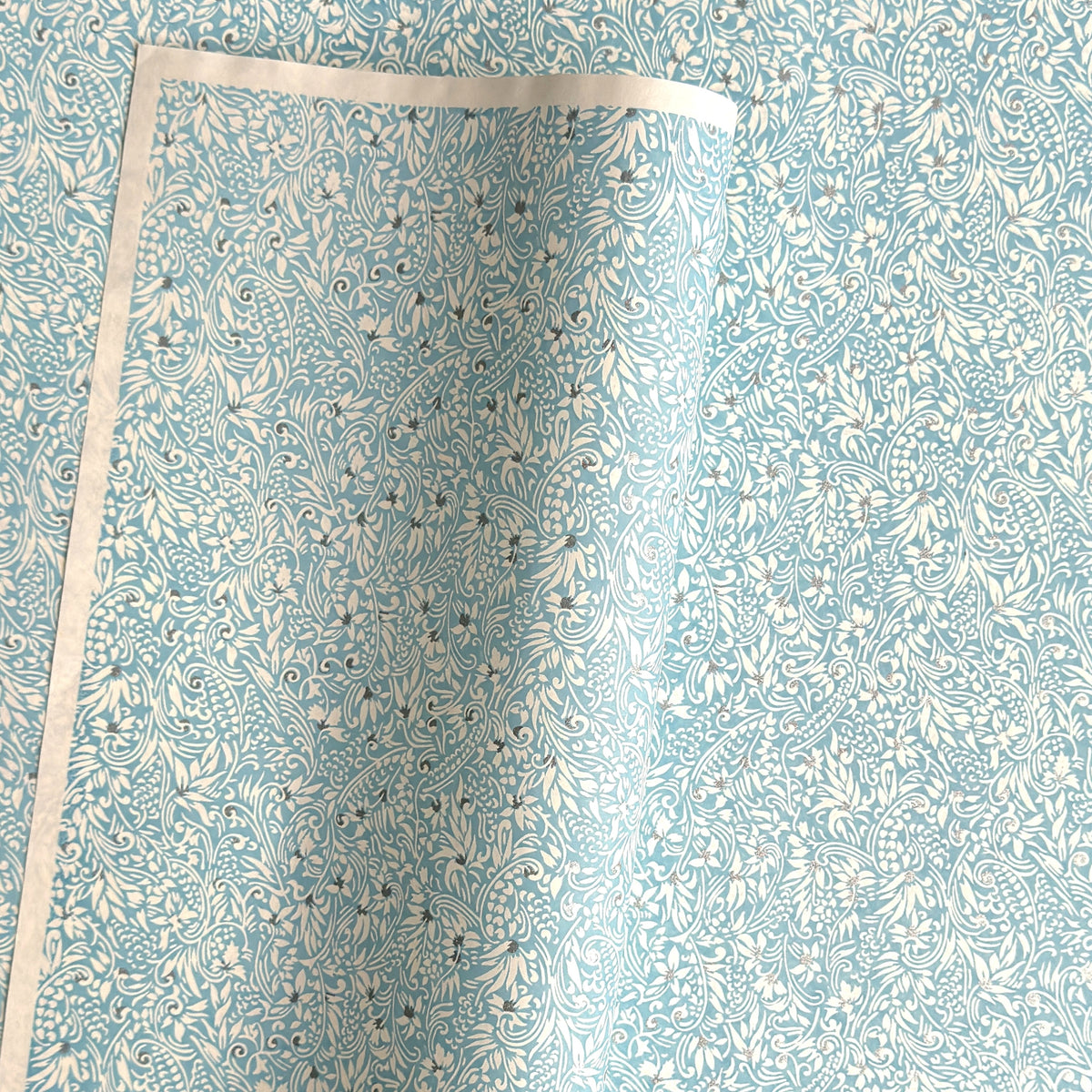Japanese chiyogami paper - silkscreen printed - light blue backdrop with a small botanical pattern in white with silver accents.