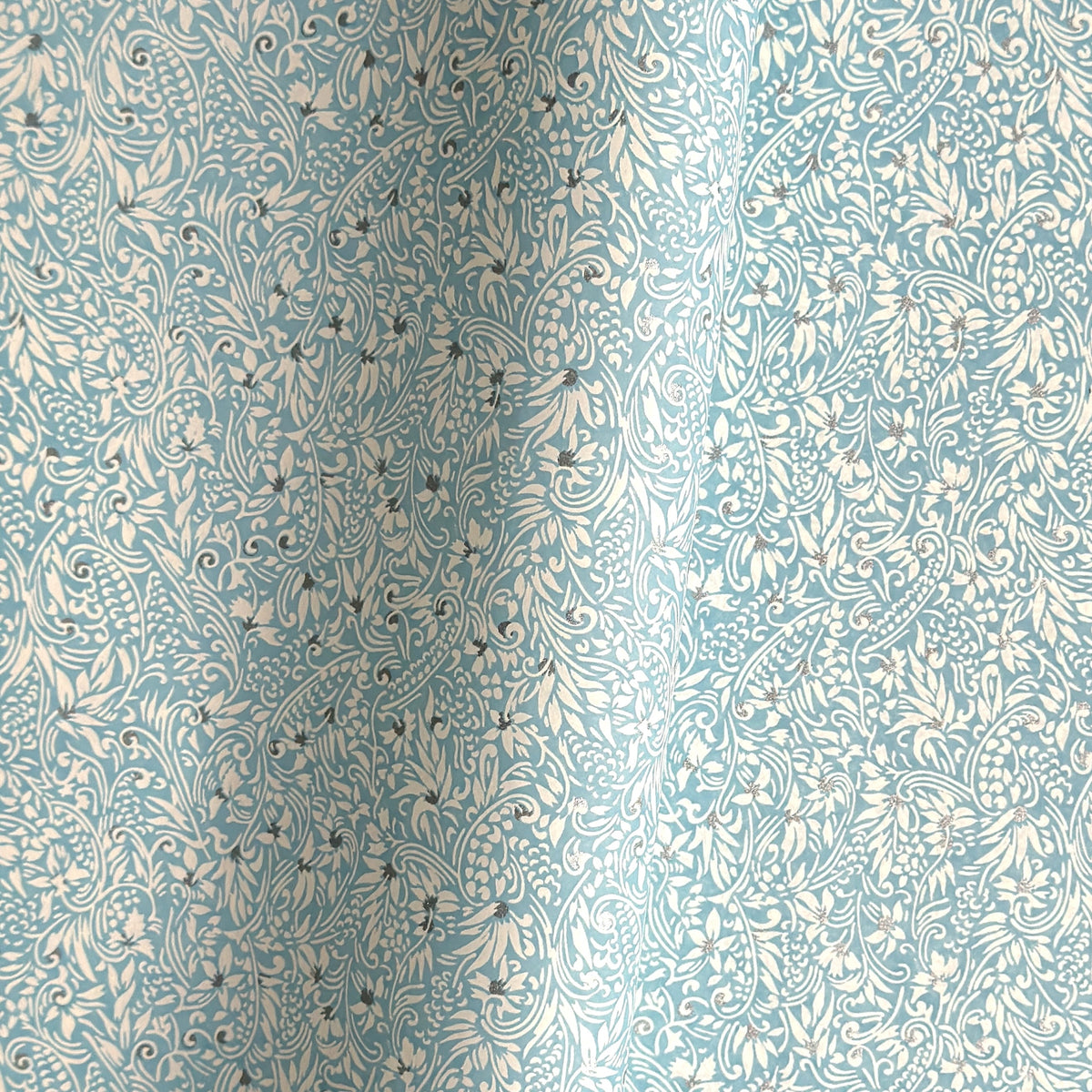 Japanese chiyogami paper - silkscreen printed - light blue backdrop with a small botanical pattern in white with silver accents.