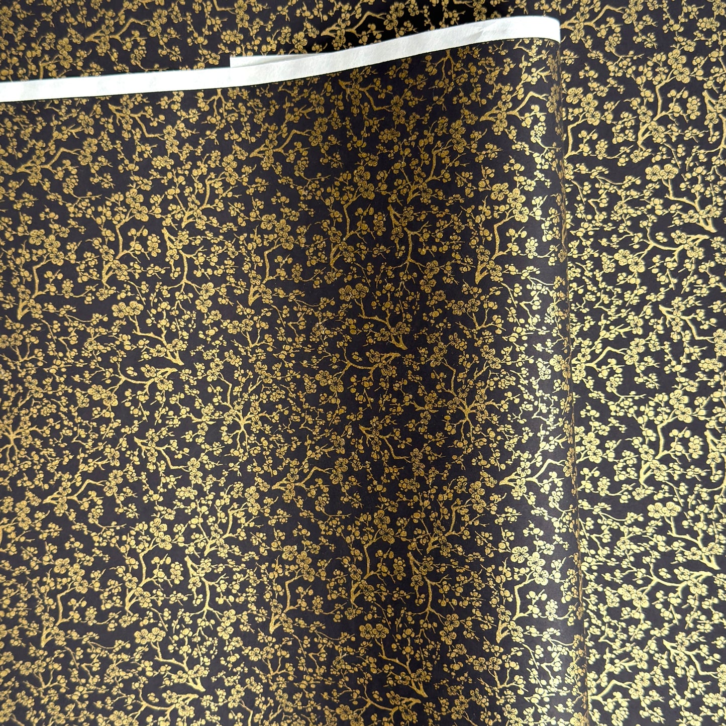 a sheet of Japanese chiyogami yuzen paper with a micro botanical pattern in gold on black