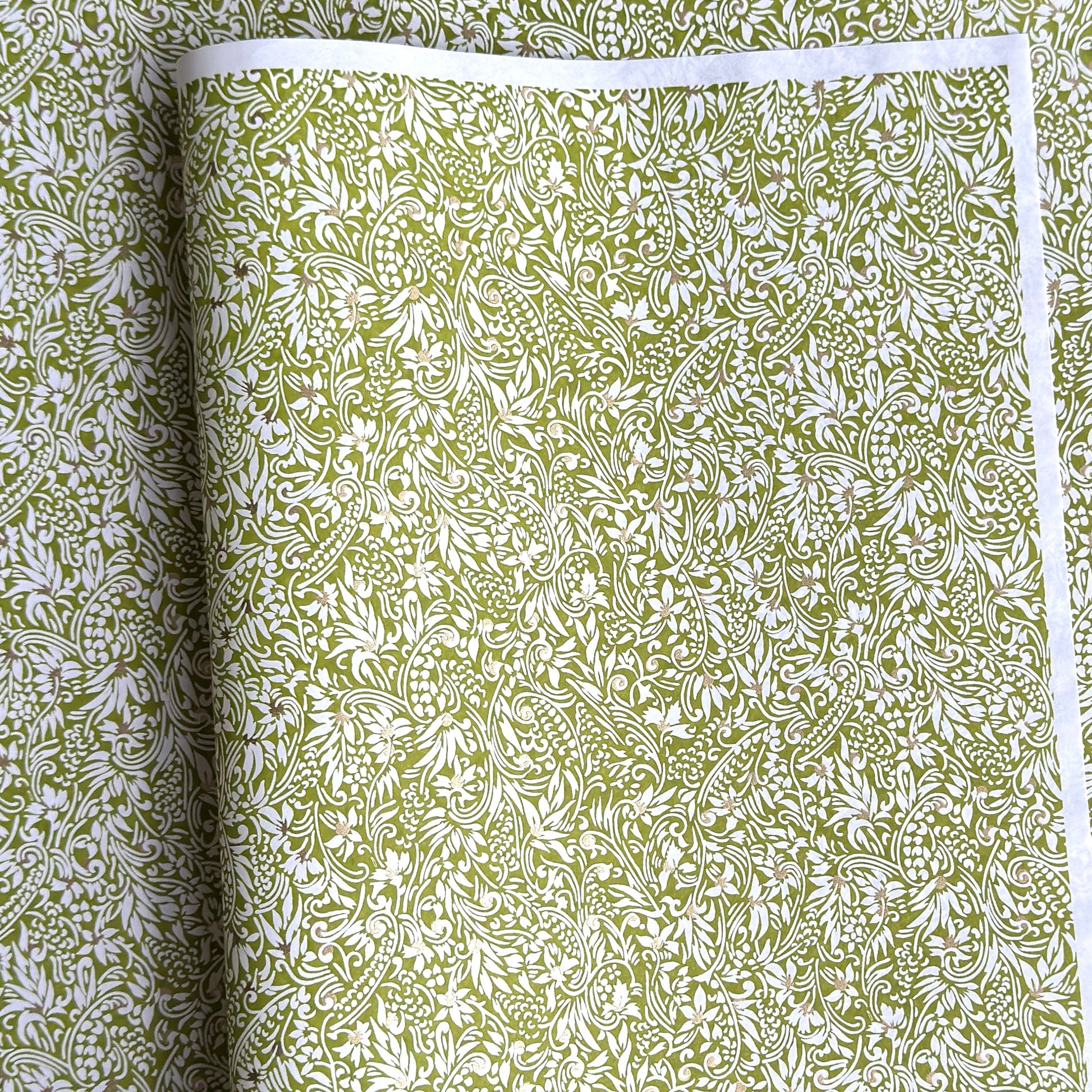 japanese silk-screen handmade paper showing green and white botanical repeat pattern with gold highlights