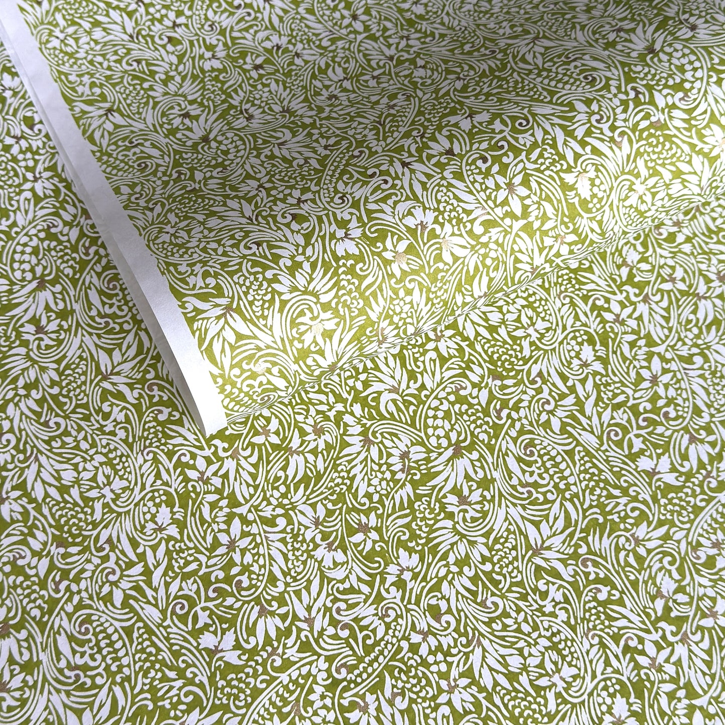 japanese silk-screen handmade paper showing green and white botanical repeat pattern with gold highlights