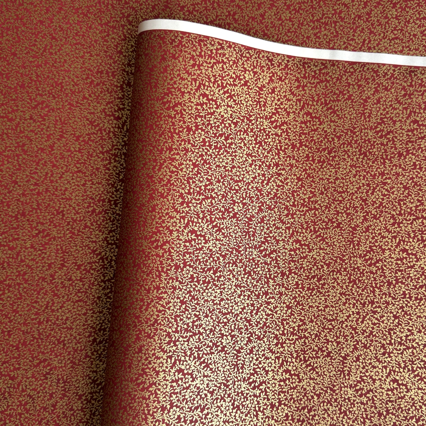 a sheet of Japanese chiyogami yuzen paper with a ditsy gold floral design on a deep red