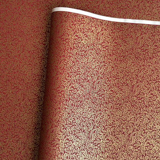 a sheet of Japanese chiyogami yuzen paper with a ditsy gold floral design on a deep red