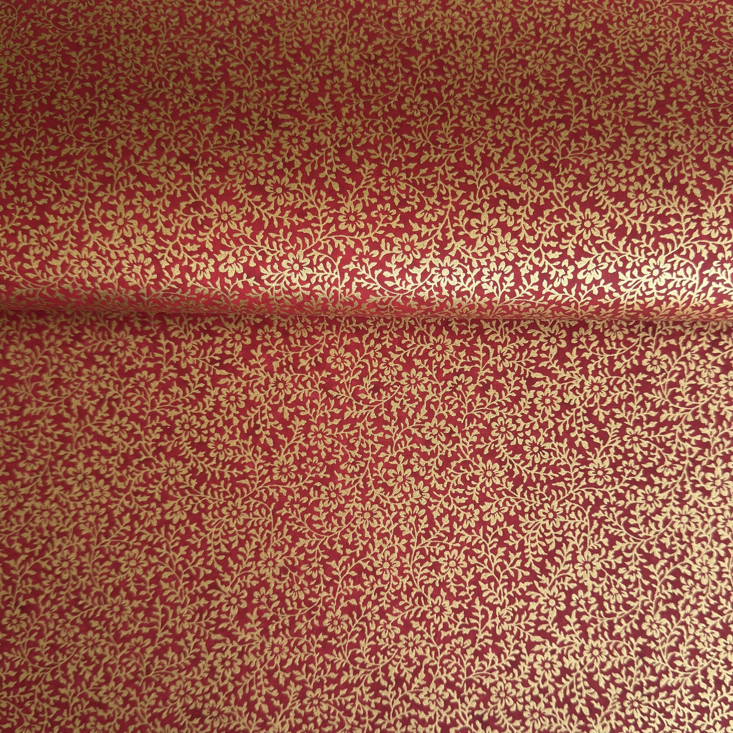 a sheet of Japanese chiyogami yuzen paper with a ditsy gold floral design on a deep red
