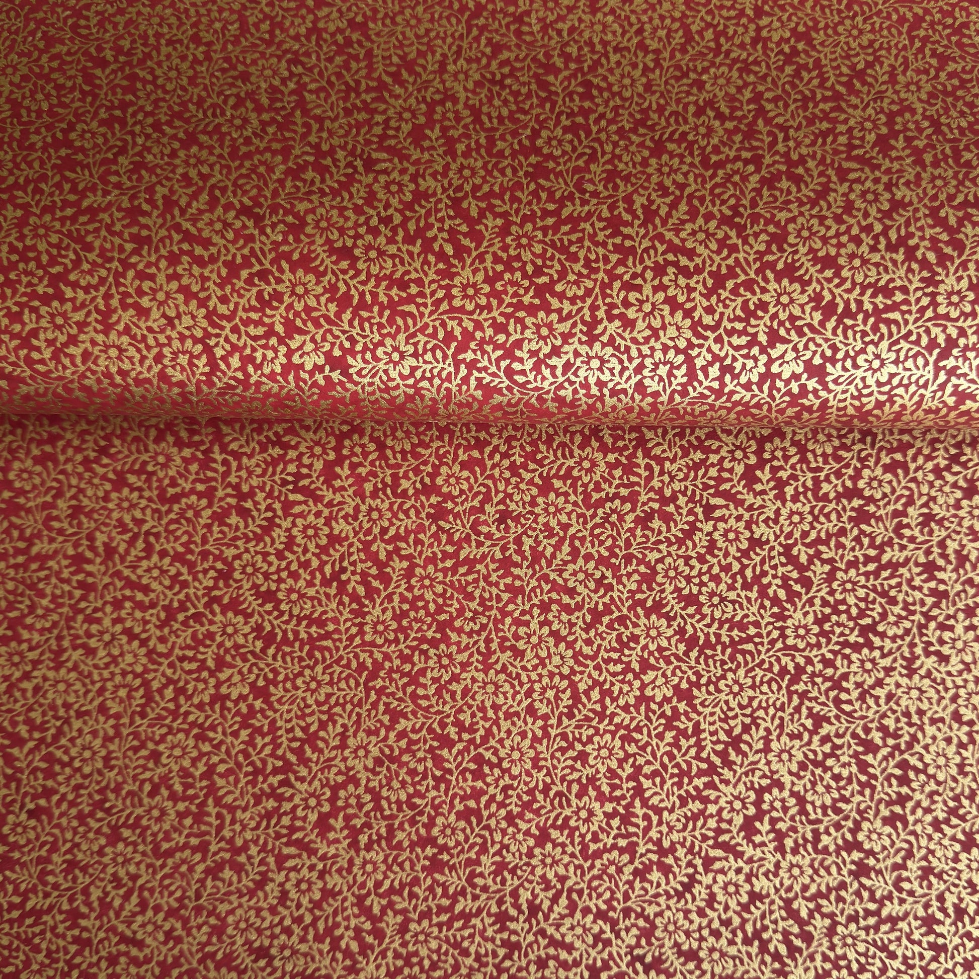a sheet of Japanese chiyogami yuzen paper with a ditsy gold floral design on a deep red