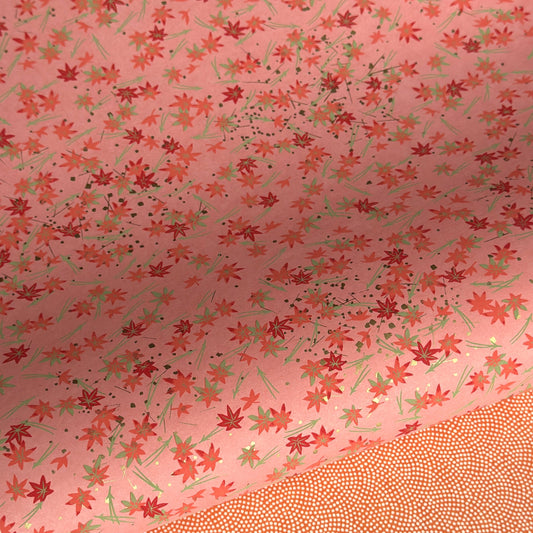 japanese silk-screen handmade paper showing pattern of red falling leaves on coral backdrop and gold highlights