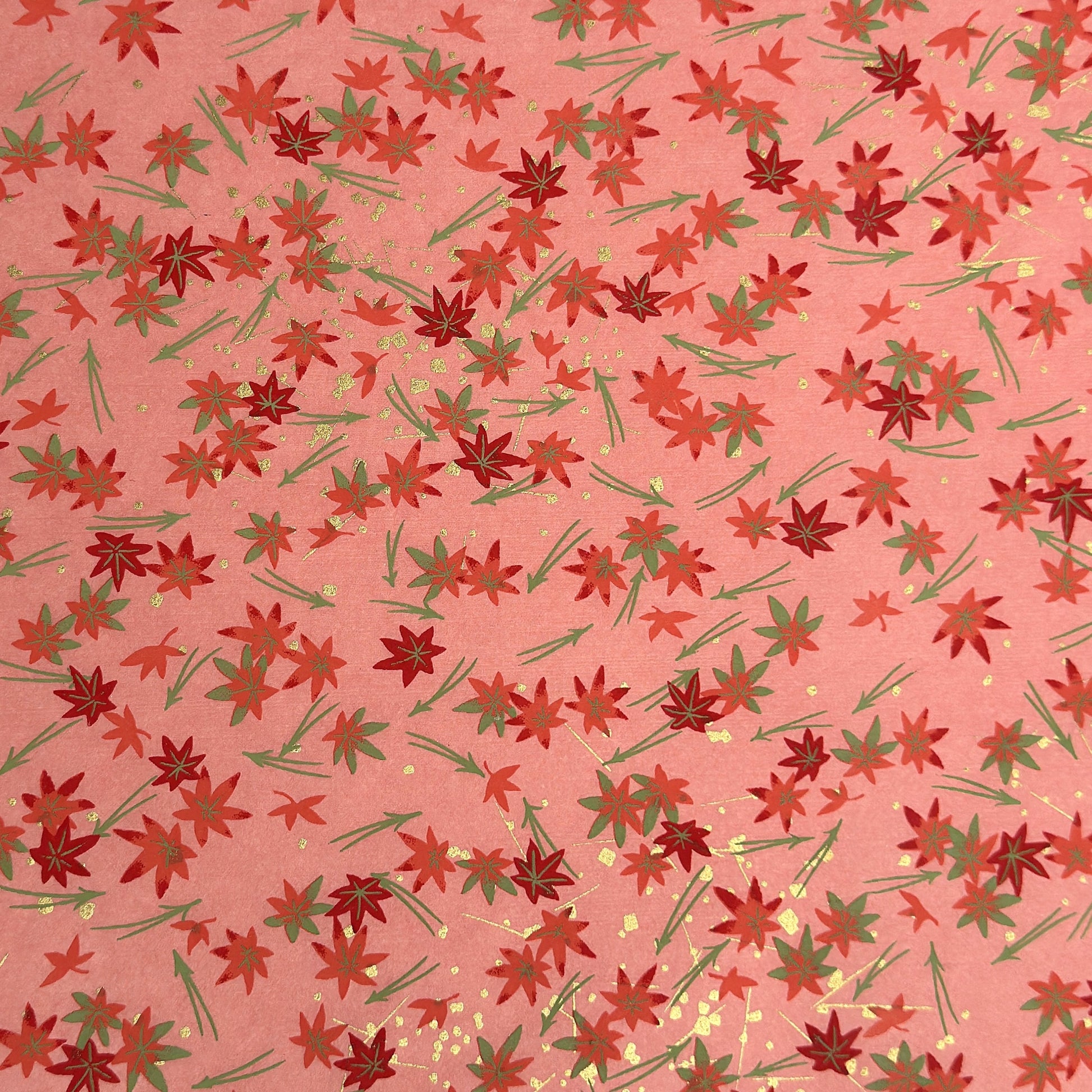 japanese silk-screen handmade paper showing pattern of red falling leaves on coral backdrop and gold highlights