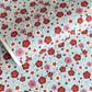 japanese silk-screen handmade paper showing red and pink plum flowers on a blue geometric backdrop