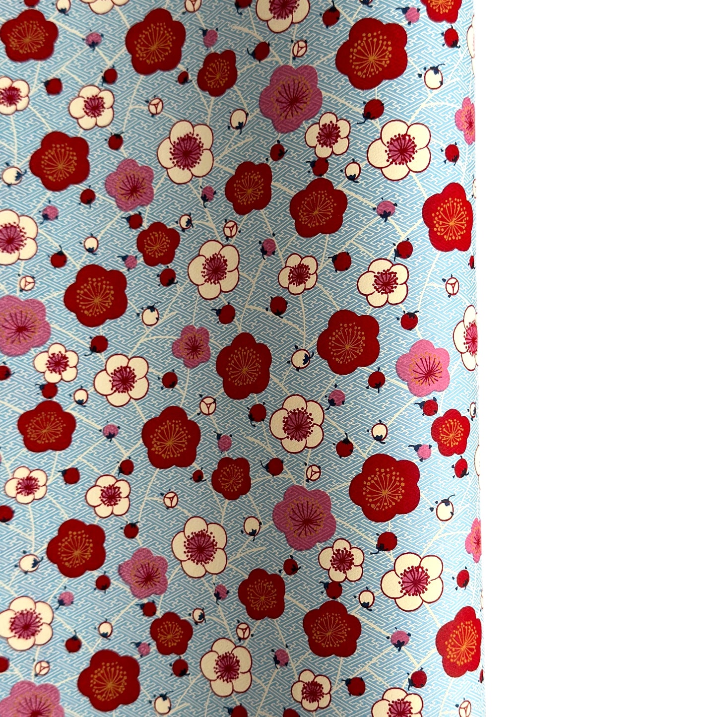 japanese silk-screen handmade paper showing red and pink plum flowers on a blue geometric backdrop