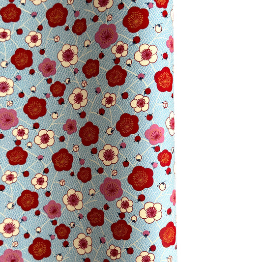 japanese silk-screen handmade paper showing red and pink plum flowers on a blue geometric backdrop