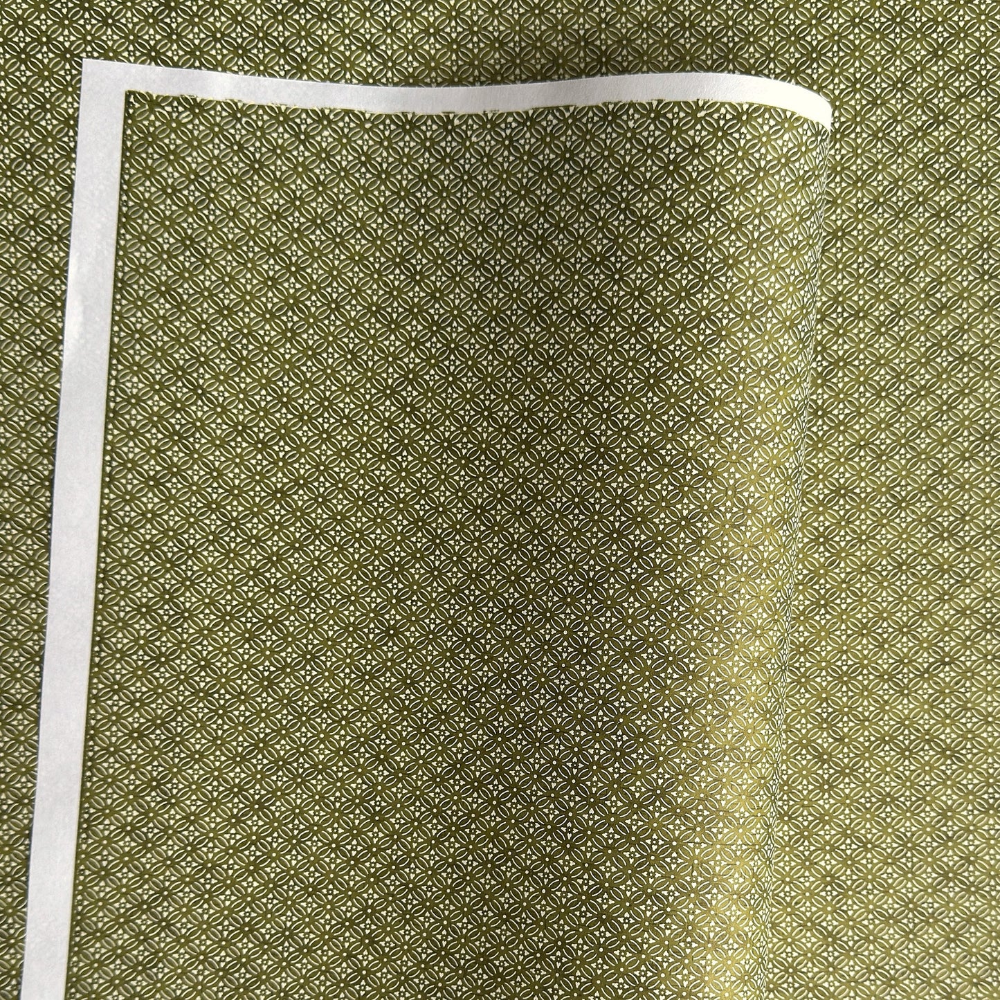 Japanese silkscreen chiyogami paper with a two-tone rich green geometric pattern on creamy white