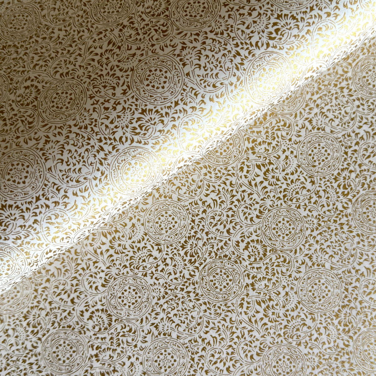Japanese silkscreen chiyogami paper with an intricate floral pattern in gold on ivory white.