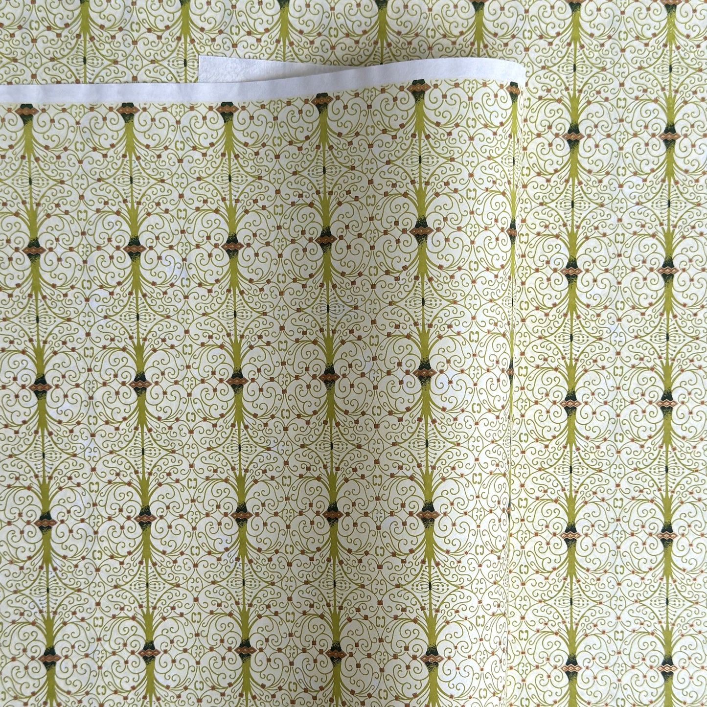 japanese silk-screen handmade paper showing green filigree pattern with gold accents