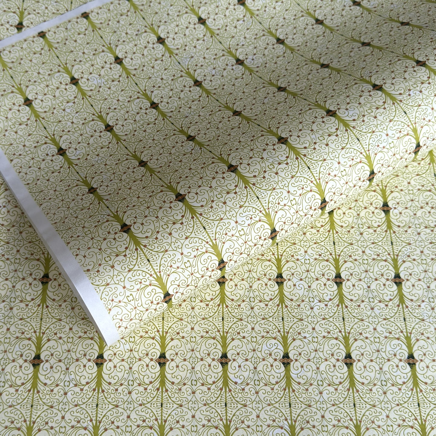 japanese silk-screen handmade paper showing green filigree pattern with gold accents