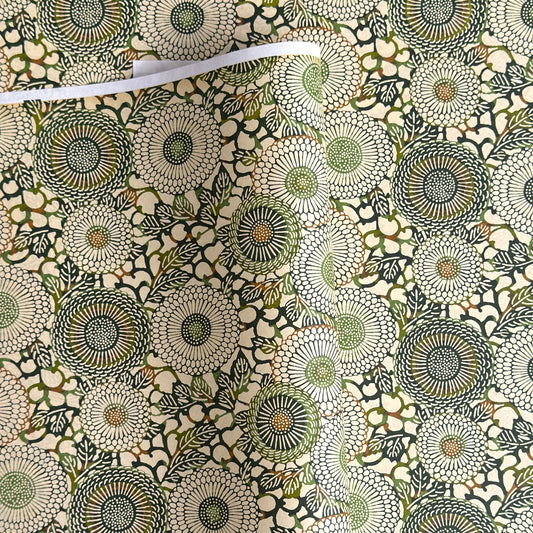 Japanese silkscreen chiyogami paper with a repeat pattern of stylised chrysanthemum flowers in tones of deep green on a buttermilk cream backdrop.