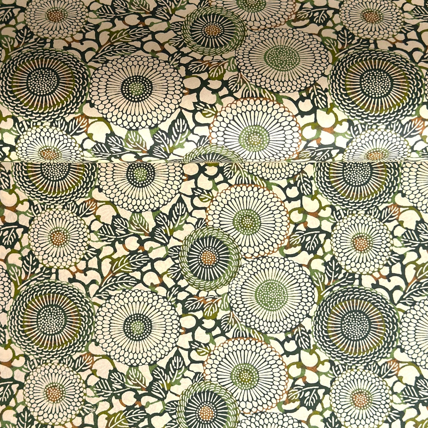 Japanese silkscreen chiyogami paper with a repeat pattern of stylised chrysanthemum flowers in tones of deep green on a buttermilk cream backdrop.