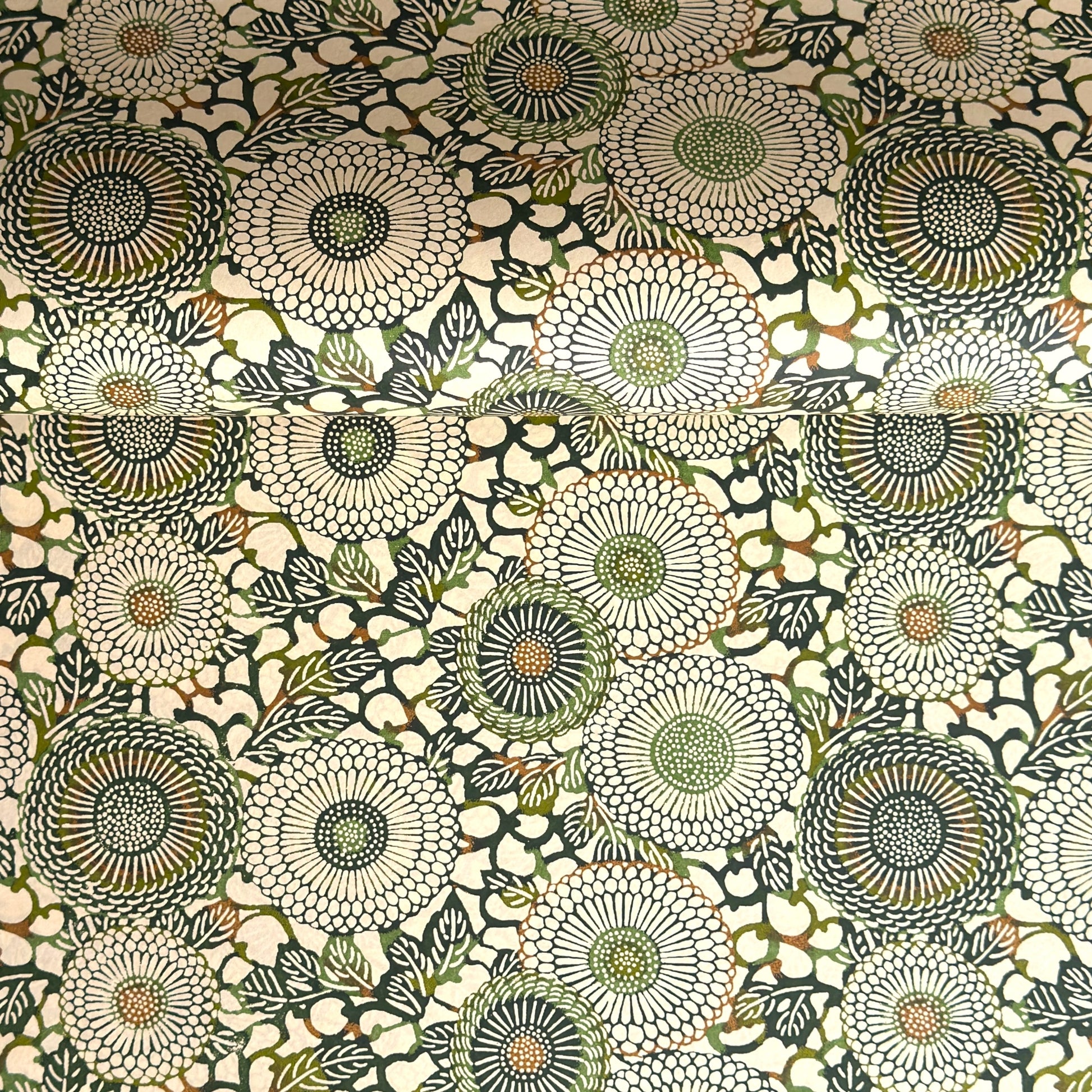 Japanese silkscreen chiyogami paper with a repeat pattern of stylised chrysanthemum flowers in tones of deep green on a buttermilk cream backdrop.