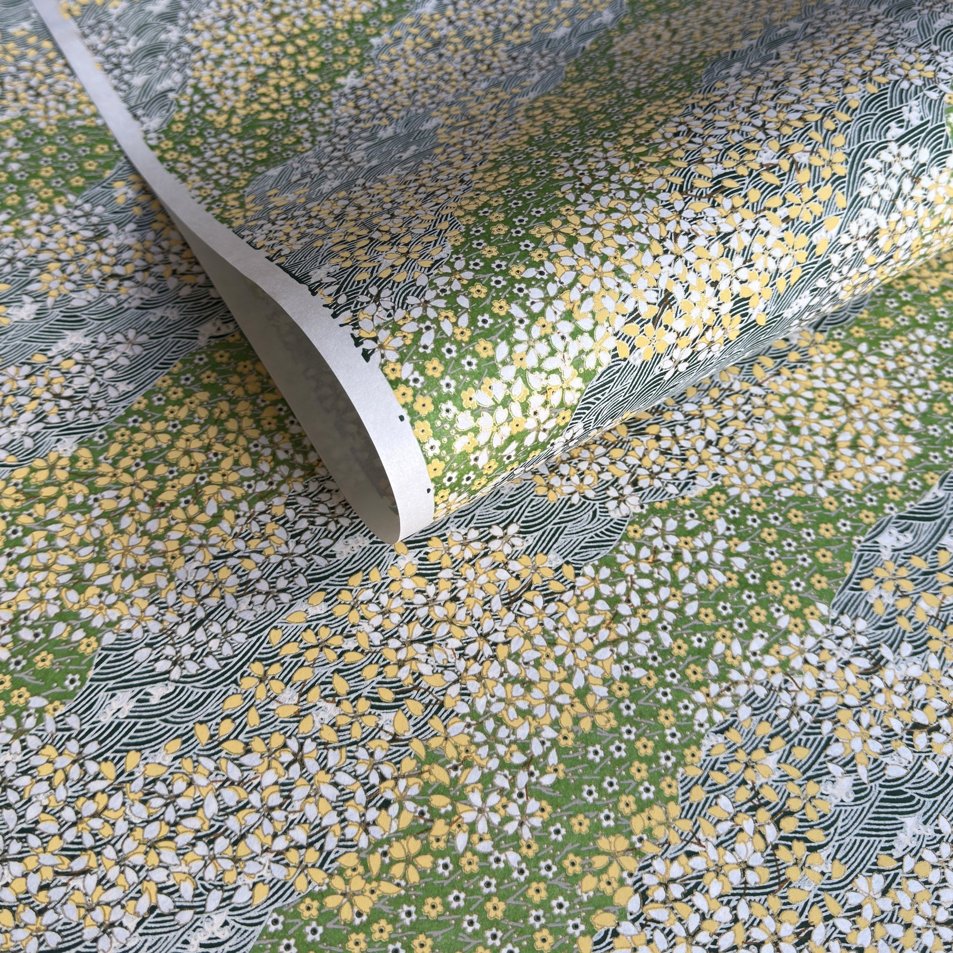 Japanese silkscreen chiyogami paper with a pattern of dark green rivers and grass green banks with an abundance of little flowers in white and yellow