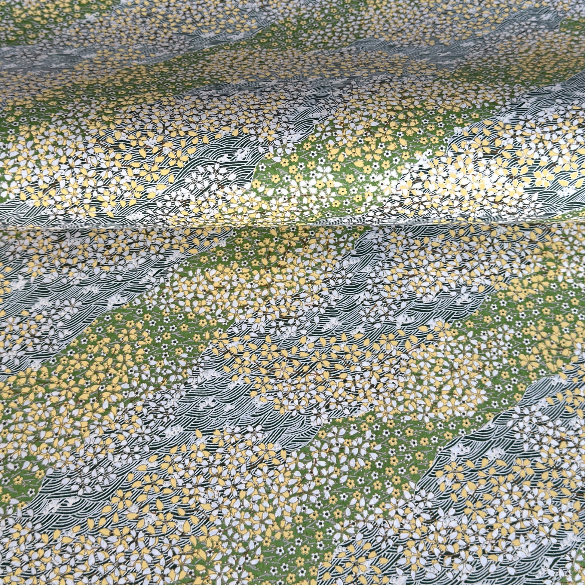 Japanese silkscreen chiyogami paper with a pattern of dark green rivers and grass green banks with an abundance of little flowers in white and yellow