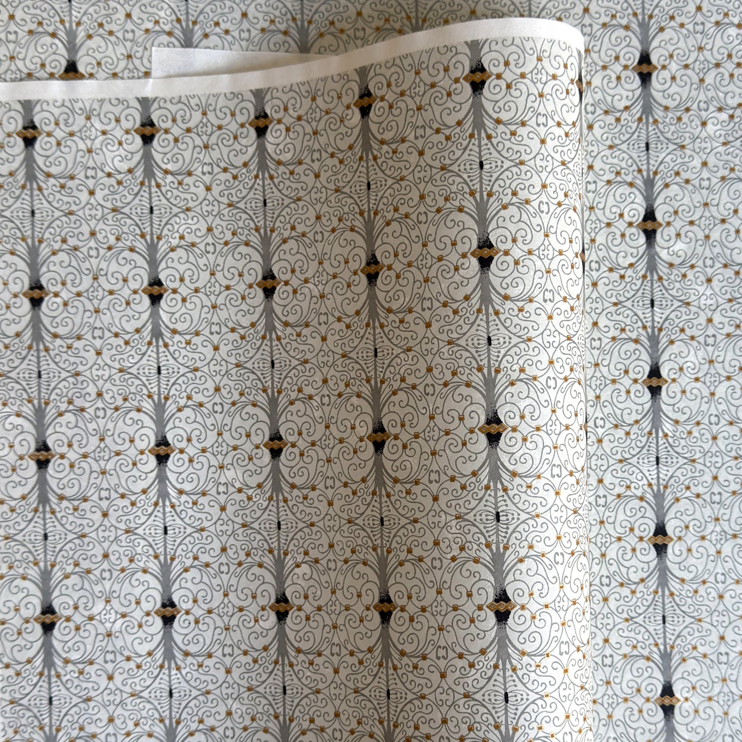 Japanese silkscreen chiyogami paper with a intricate filigree trellis design in grey with gold accent