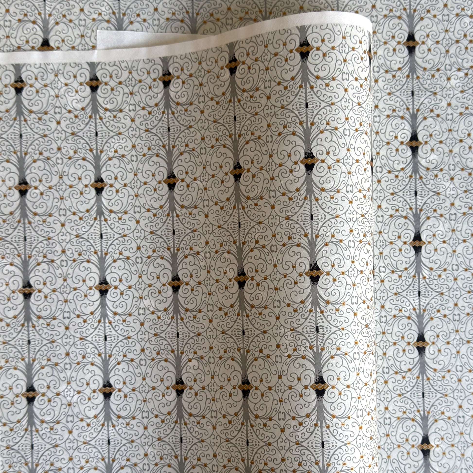 Japanese silkscreen chiyogami paper with a intricate filigree trellis design in grey with gold accent