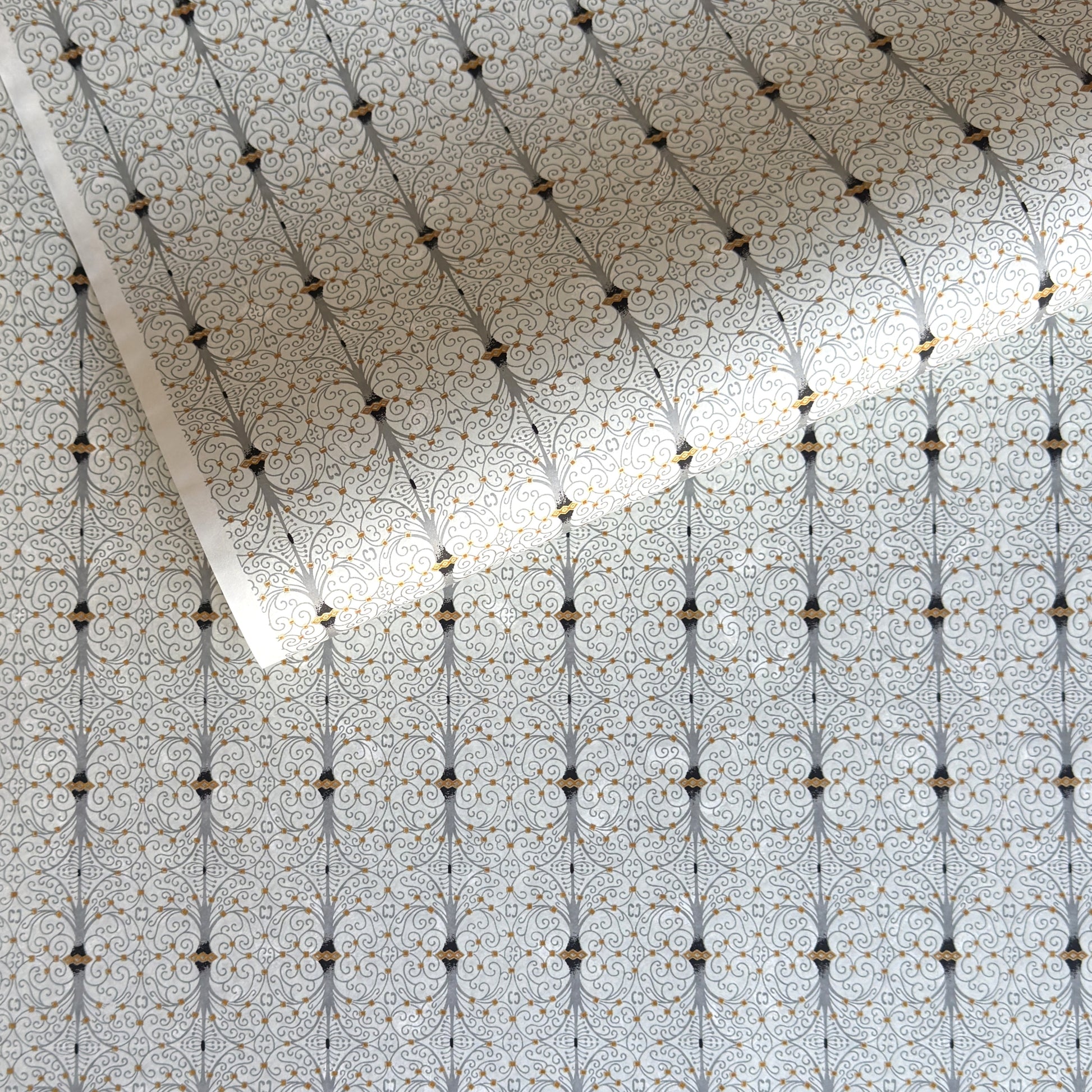 Japanese silkscreen chiyogami paper with a intricate filigree trellis design in grey with gold accent