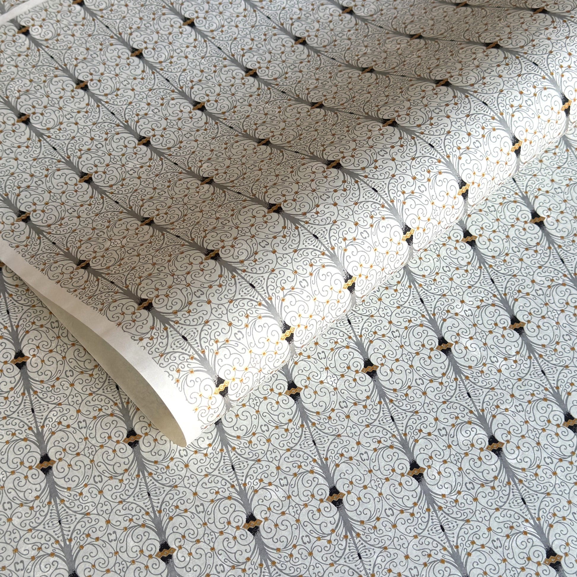 Japanese silkscreen chiyogami paper with a intricate filigree trellis design in grey with gold accent