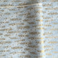 a sheet of Japanese silkscreen printed chiyogami paper with waves of tiny white and gold flowers on a soft aqua background with a dusting of gold.
