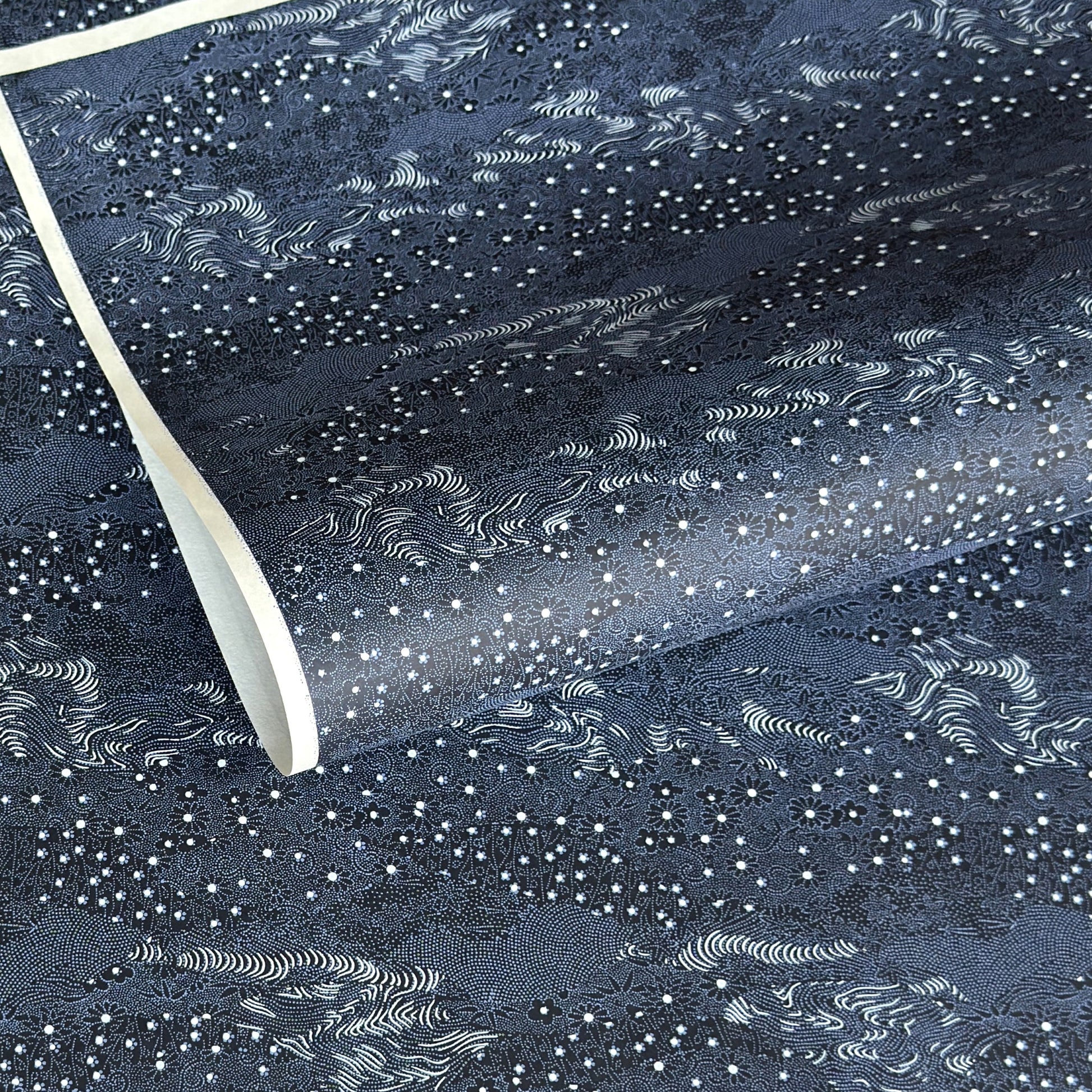 Japanese chiyogami paper.  Inky blue with a subtle pattern of a riverbank of flowers.  