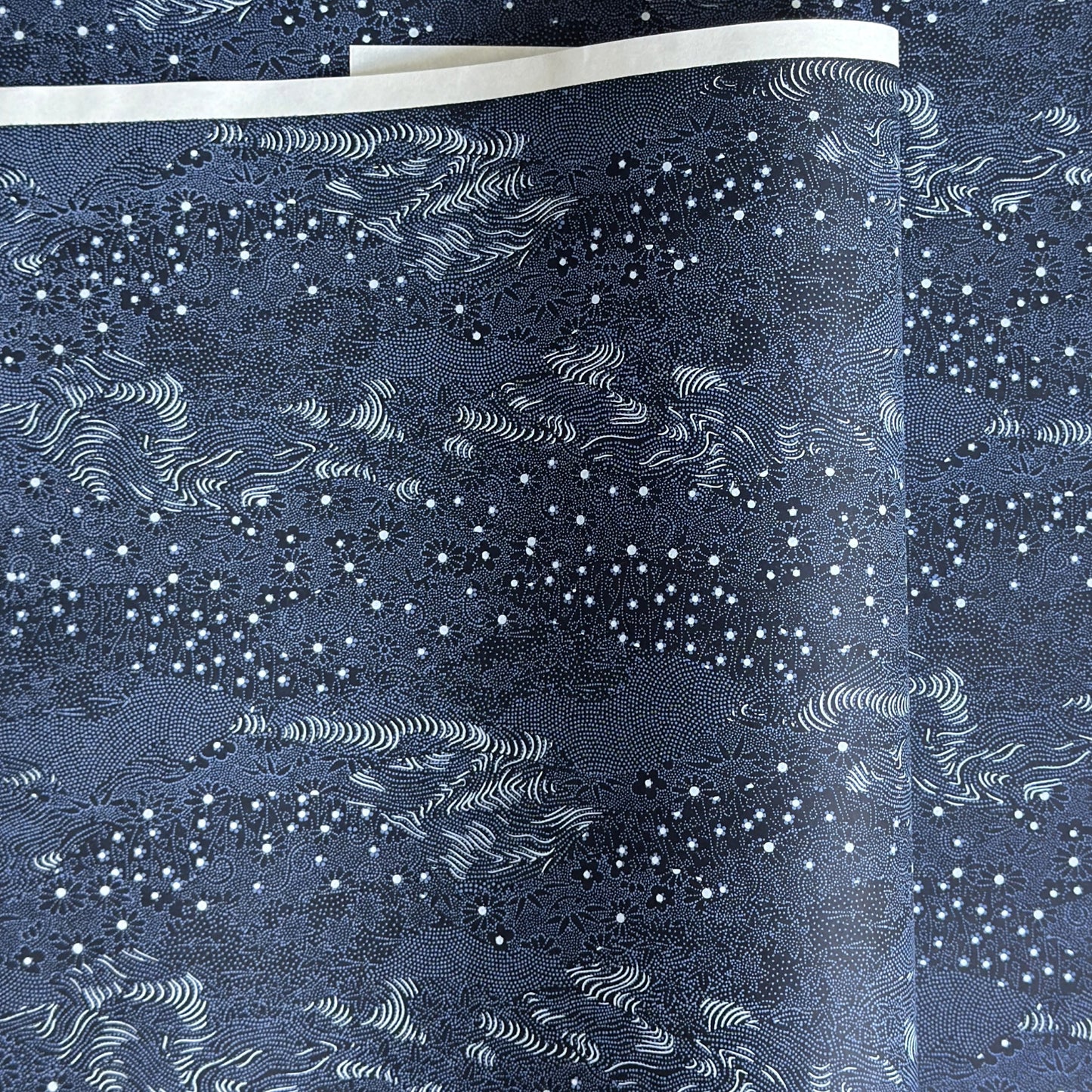 Japanese chiyogami paper.  Inky blue with a subtle pattern of a riverbank of flowers.  