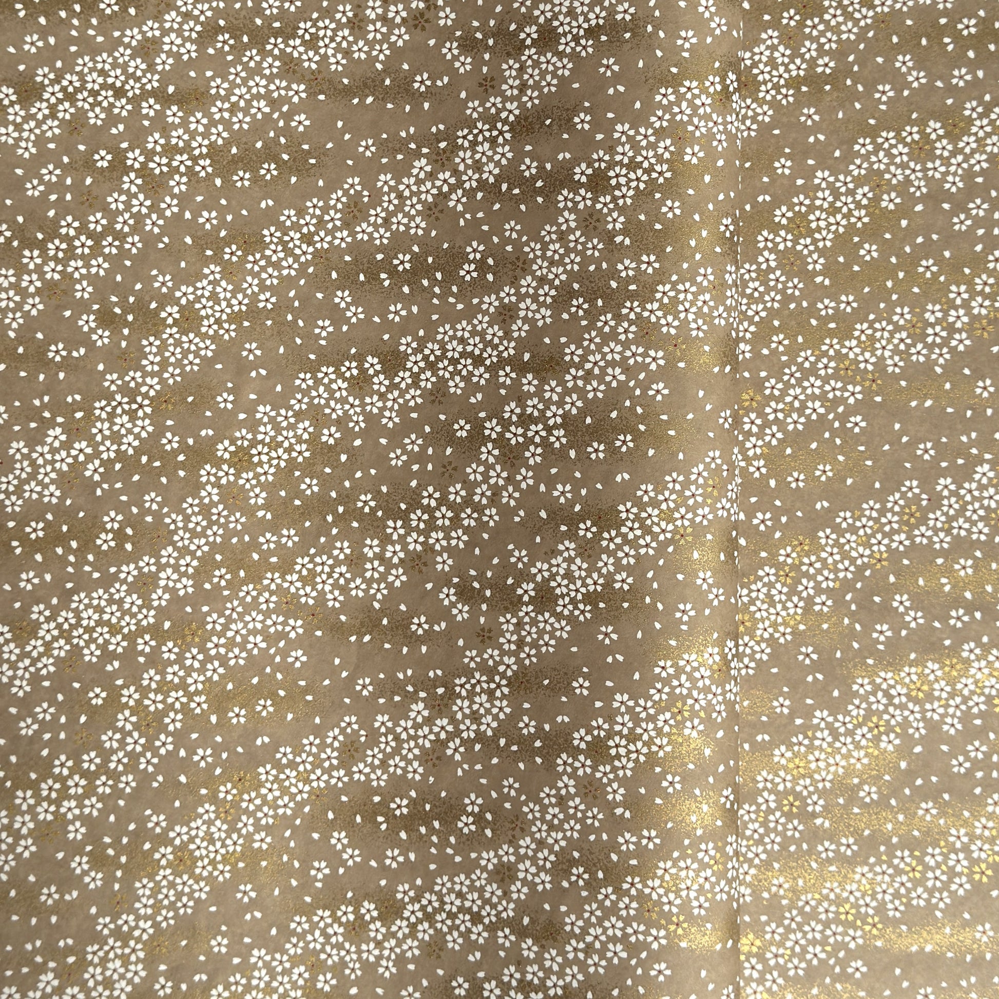 a sheet of Japanese silkscreen printed chiyogami paper with waves of tiny white and gold flowers on a soft taupe background with a dusting of gold.