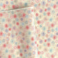 japanese chiyogami silkscreen printed paper with a pattern of fireworks in reds, pinks and lilacs on an ivory background.