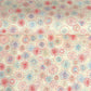 japanese chiyogami silkscreen printed paper with a pattern of fireworks in reds, pinks and lilacs on an ivory background.
