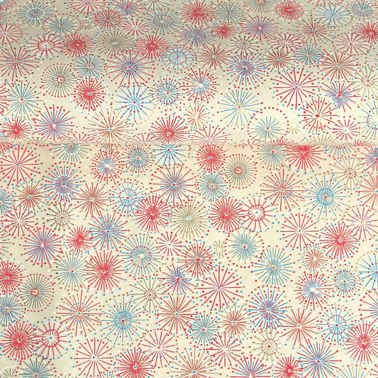 japanese chiyogami silkscreen printed paper with a pattern of fireworks in reds, pinks and lilacs on an ivory background.