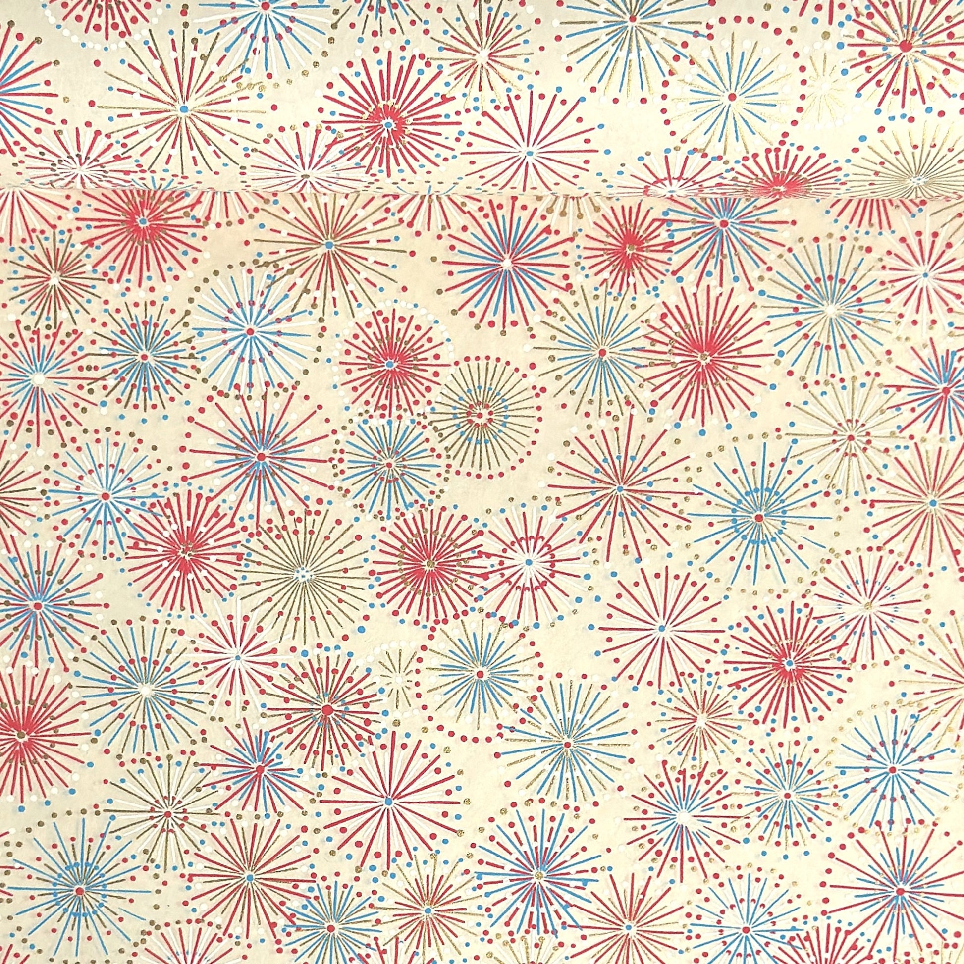 japanese chiyogami silkscreen printed paper with a pattern of fireworks in reds, pinks and lilacs on an ivory background.