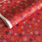 japanese chiyogami silkscreen printed paper with a pattern of fireworks in golds and purples on a red background.