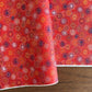 japanese chiyogami silkscreen printed paper with a pattern of fireworks in golds and purples on a red background.