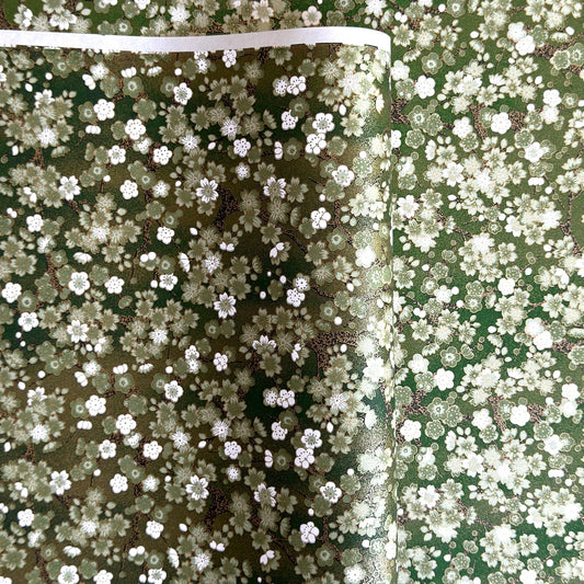Japanese chiyogami paper with white and pale green blossom flowers on dark green backdrop.