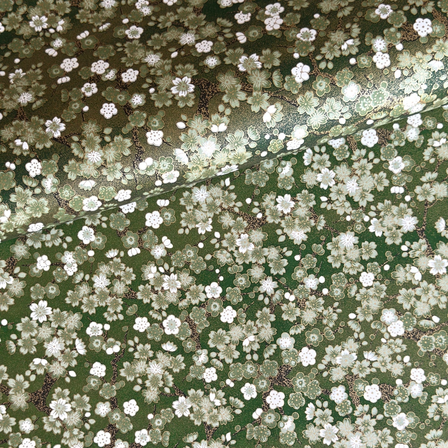 Japanese chiyogami paper with white and pale green blossom flowers on dark green backdrop.