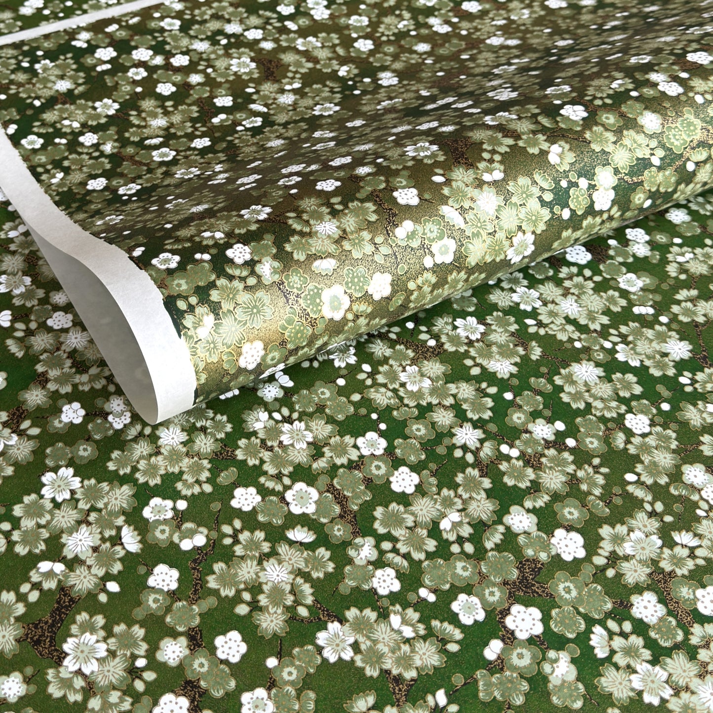 Japanese chiyogami paper with white and pale green blossom flowers on dark green backdrop.