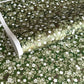 Japanese chiyogami paper with white and pale green blossom flowers on dark green backdrop.