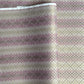 Japanese chiyogami silkscreen printed paper with rows of small flower motifs in purple, lilac and white on a taupe background with gold accents.