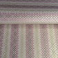 Japanese chiyogami silkscreen printed paper with rows of small flower motifs in purple, lilac and white on a taupe background with gold accents.