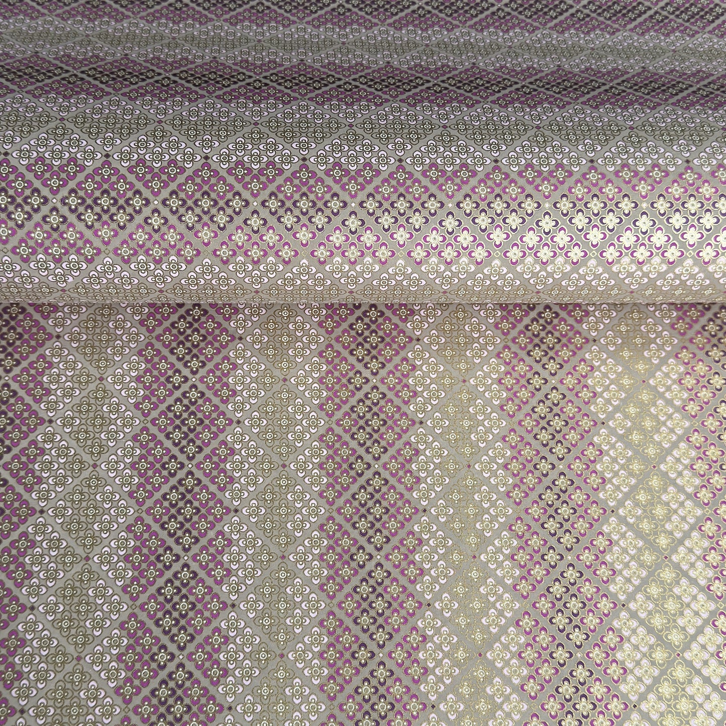 Japanese chiyogami silkscreen printed paper with rows of small flower motifs in purple, lilac and white on a taupe background with gold accents.