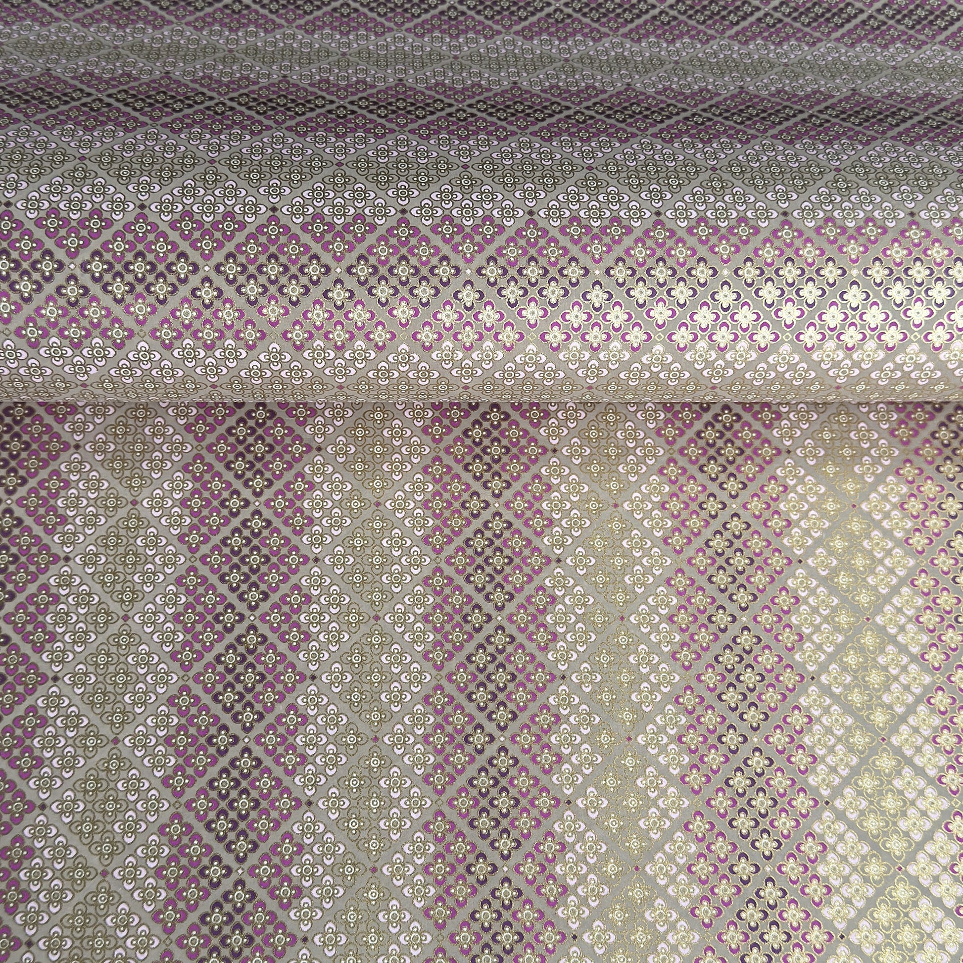 Japanese chiyogami silkscreen printed paper with rows of small flower motifs in purple, lilac and white on a taupe background with gold accents.