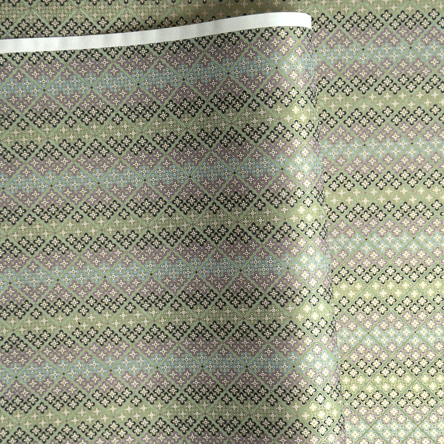 Japanese silkscreen chiyogami paper with a repeat pattern of stripes of a small floral motif in black, lilac and blue on a moss green backdrop