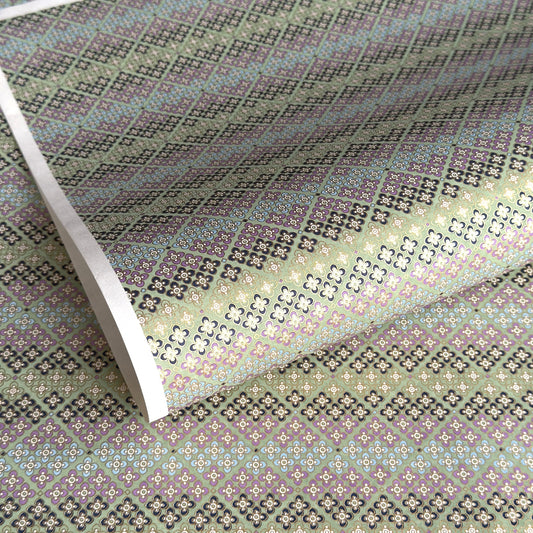 Japanese silkscreen chiyogami paper with a repeat pattern of stripes of a small floral motif in black, lilac and blue on a moss green backdrop