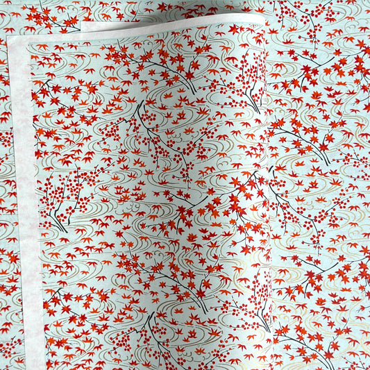 a sheet of japanese silkscreen printed chiyogami paper with a pattern of gold rivers, red falling leaves on a soft aqua background