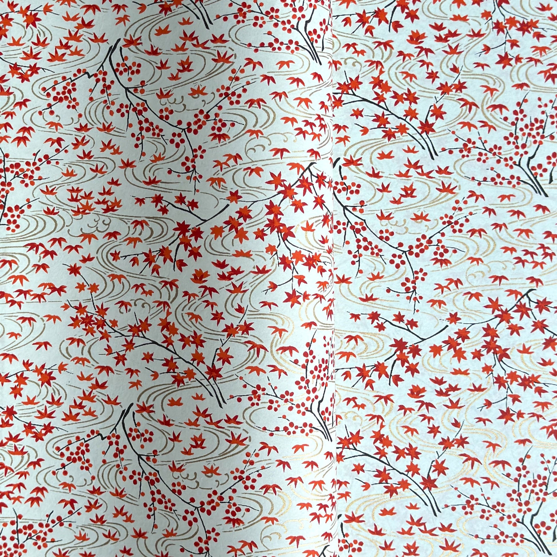 a sheet of japanese silkscreen printed chiyogami paper with a pattern of gold rivers, red falling leaves on a soft aqua background