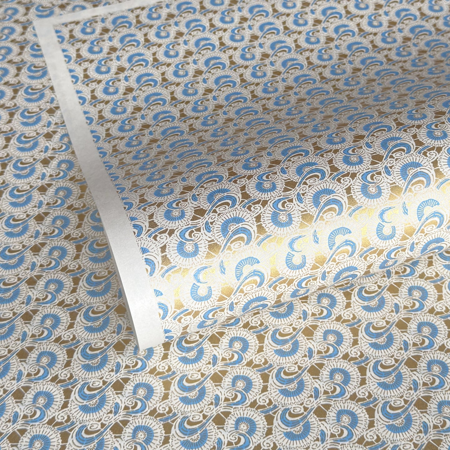Japanese silkscreen chiyogami paper with a repeat floral pattern in gold an cerulean blue